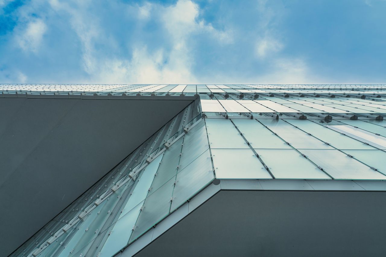 Contemporary glass facade in Oslo against blue sky, showcasing urban architectural design.